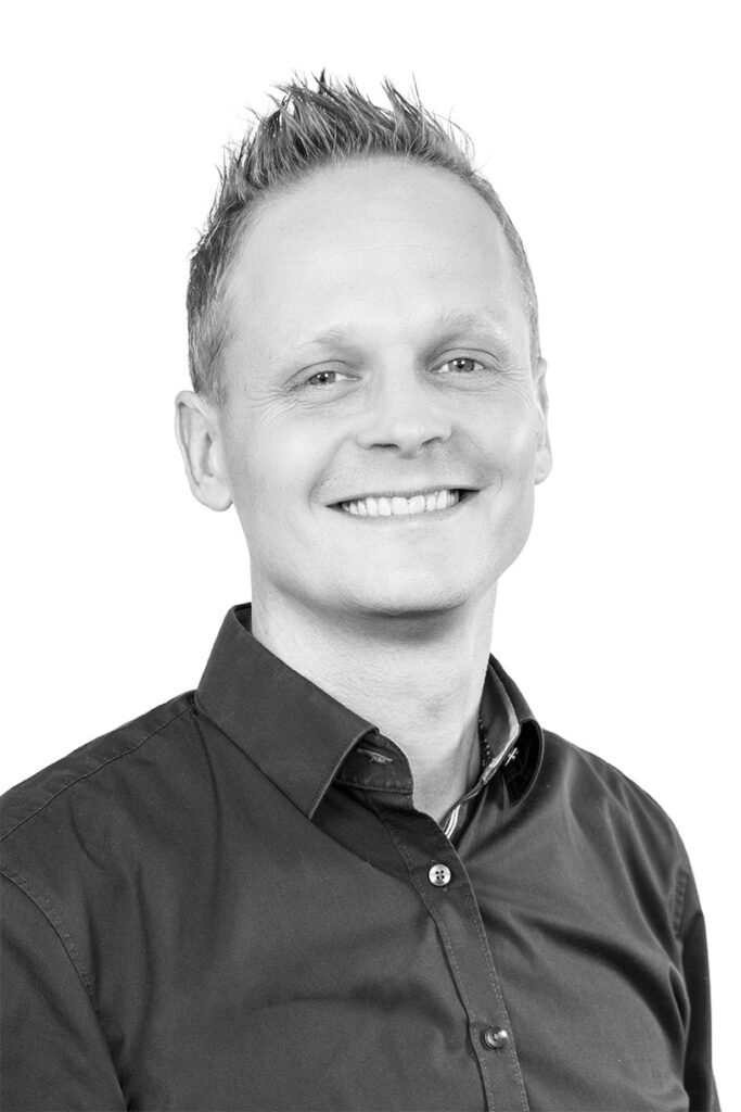 Portrætfoto i sort/hvid af salgsdirektør og kontakt i Lithomex Anders Roed i mørk skjorte på hvid baggrund